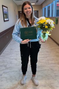 March 2026 Daisy Award winner with flowers and award