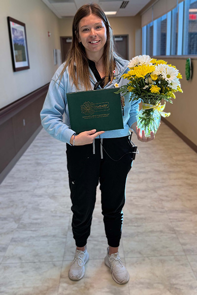 March 2026 Daisy Award winner with flowers and award