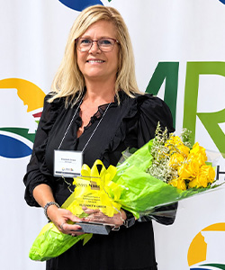 Elizabeth Green holding a bouquet of flowers in front of a MRHA backdrop