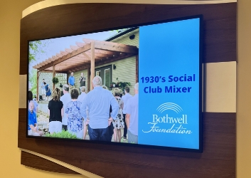 One of the TVs on the donor wall showing the 1930s Social Club Mixer slideshow