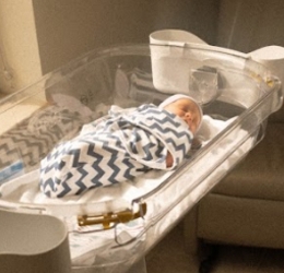 A newborn baby swaddled in a bassinet
