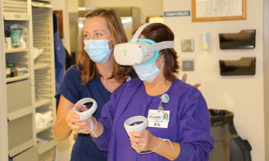 Laura Weisenburger, Nursing Education educator/recruiter, assists Liz Hackett, Same Day Surgery/PACU charge nurse, on how to use the VR training system.