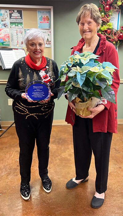 Shirley Evans, right, presented Sue Heckart, left, with a plaque and flowers from the Bothwell Regional Health Center Auxiliary in recognition of Heckart’s years of dedicated service and contributions during the Auxiliary’s Christmas Tea on Dec. 11.